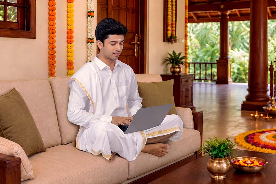 Young Indian man working on laptop from home during Onam festival
