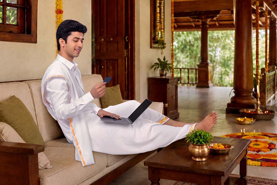 Kerala man using laptop on heritage home swing during Onam