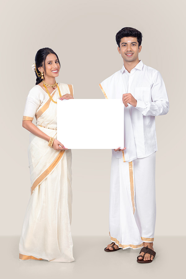 Indian couple holding blank white signboard in traditional Onam attire