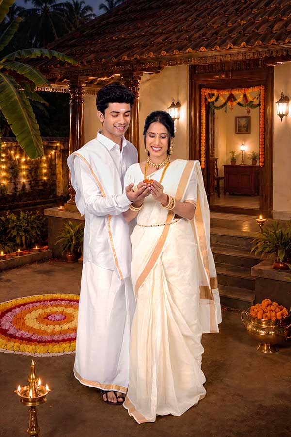 Kerala couple lighting traditional oil lamp during Onam evening celebration