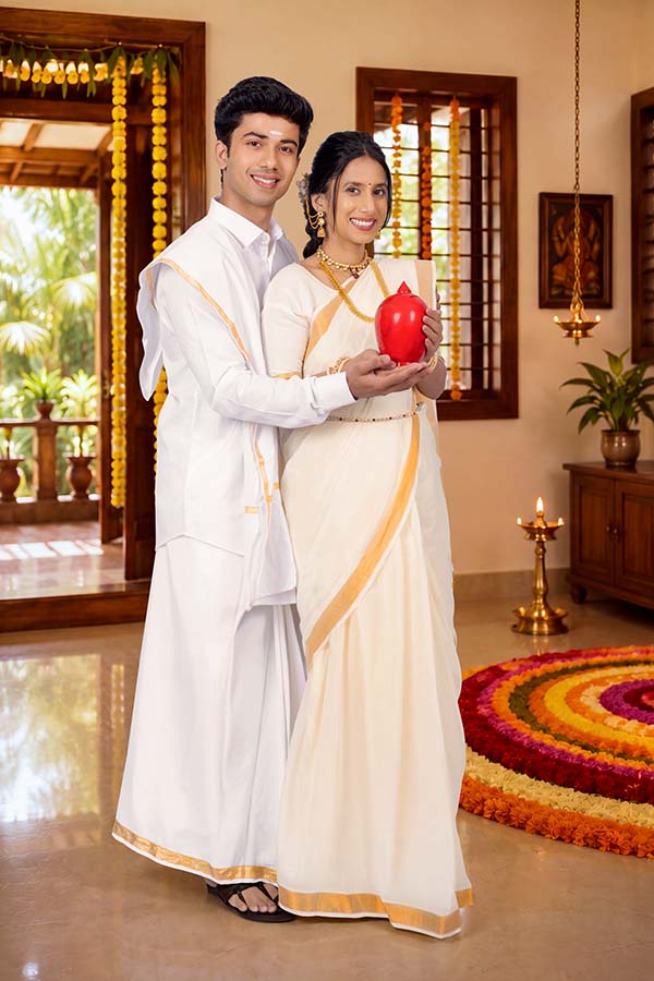 Indian couple holding traditional red gullak during Onam festival