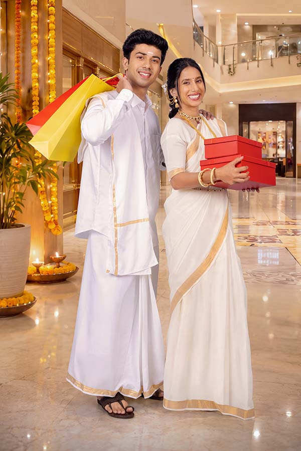 Indian couple carrying festive shopping bags and gift boxes during Onam