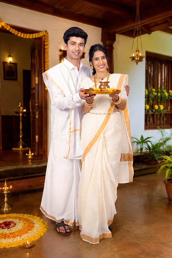 Indian couple presenting traditional Onam pooja thali with kalash
