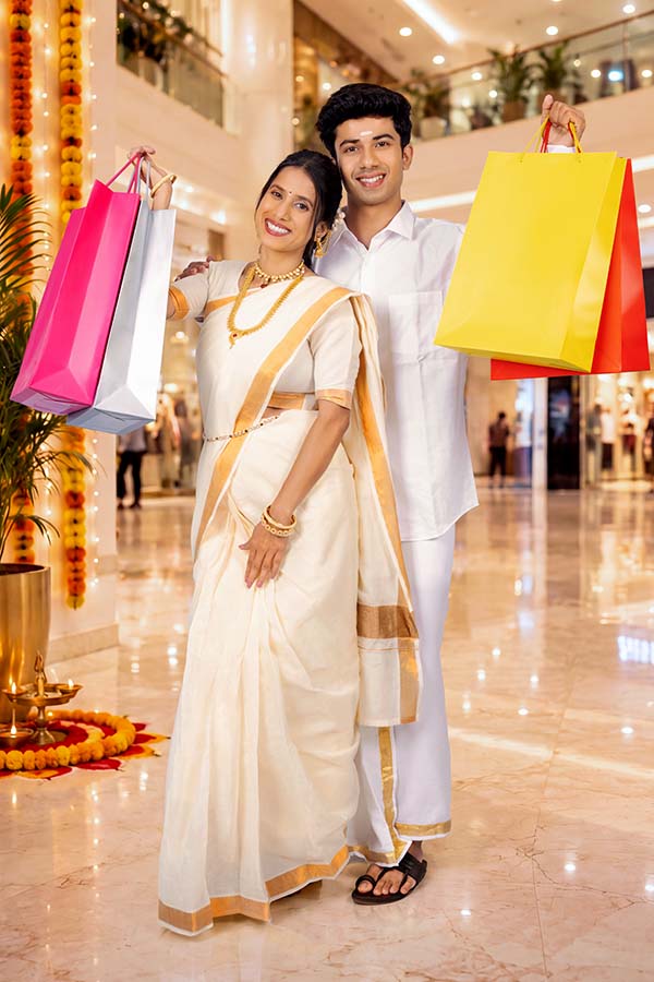 Happy Indian couple displaying colourful shopping bags after Onam shopping