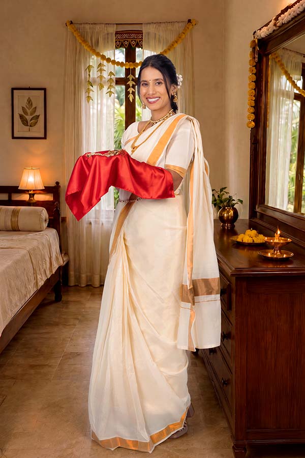 Woman presenting traditional Onam gift wrapped in red silk cloth at Kerala home