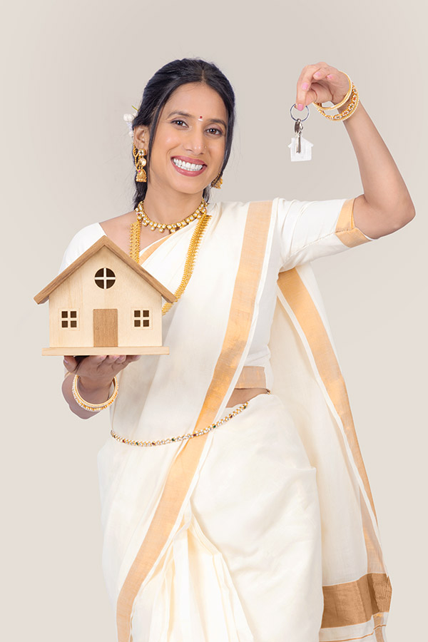 Indian woman holding wooden house model and home key