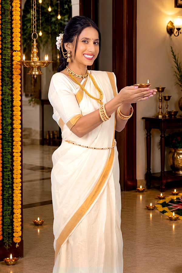 Woman holding illuminated oil lamp during Onam festival celebration