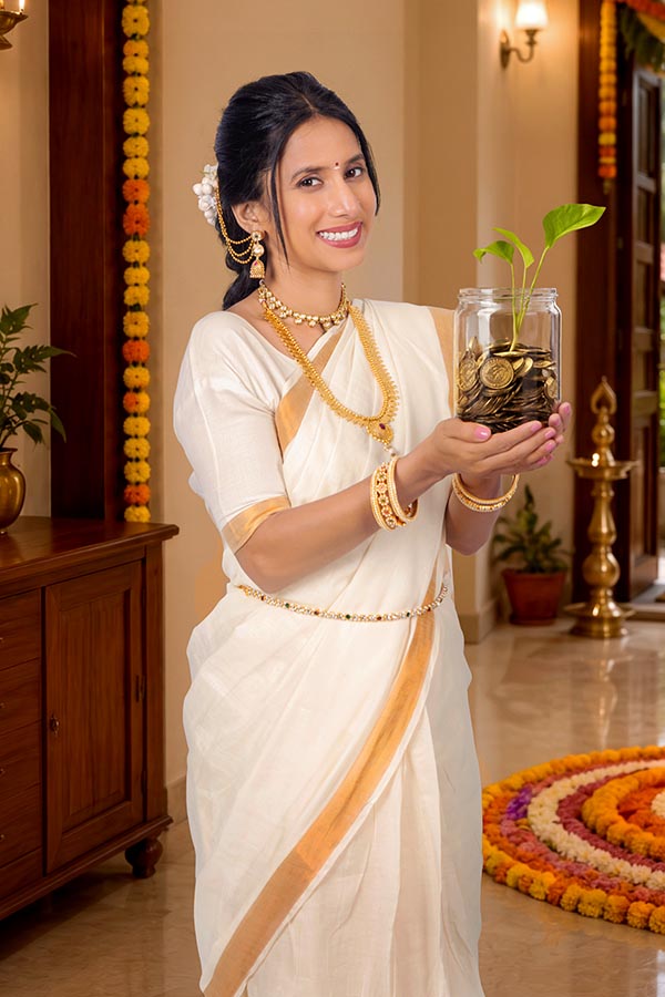 Woman holding savings jar with growing plant during Onam festival