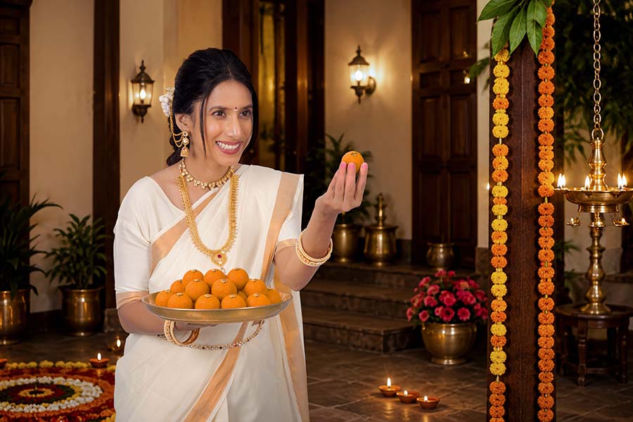 Indian woman offering traditional Onam laddus on festive platter