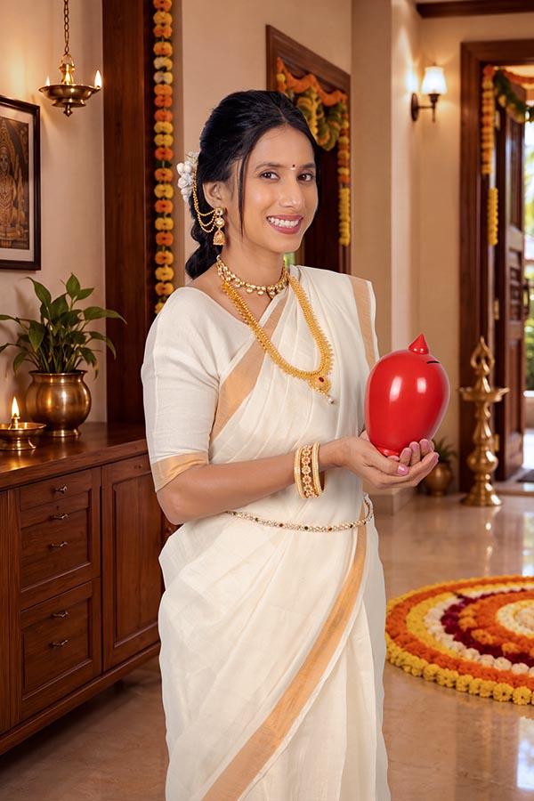 Smiling Indian woman holding traditional red gullak during Onam festival