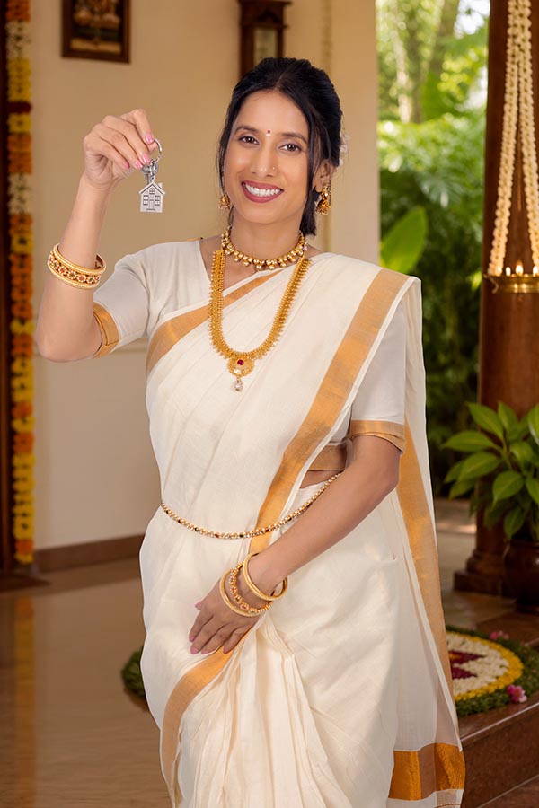 Indian woman holding house key celebrating new home during Onam