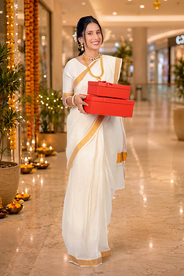 Woman carrying festive gift boxes while shopping during Onam celebration