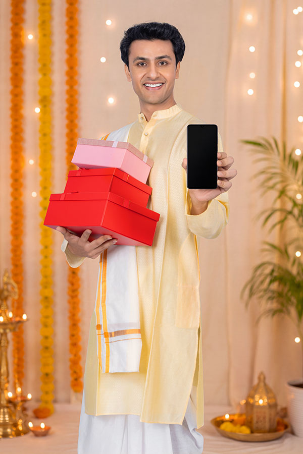 Indian man holding gift boxes and smartphone during Durga Puja