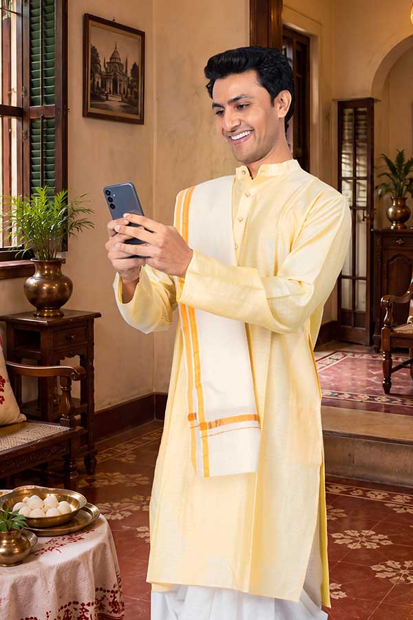 Indian man using smartphone during Durga Puja celebration at home