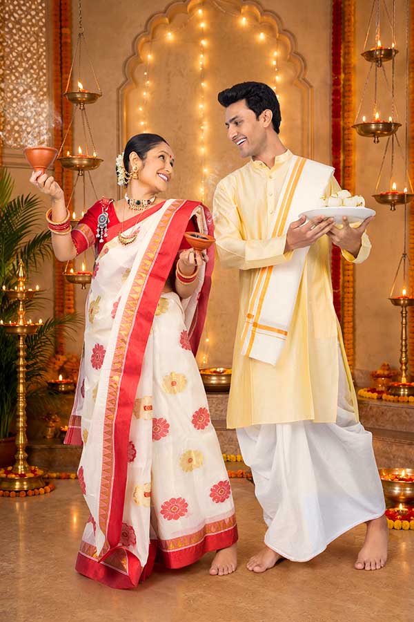 Indian couple celebrating Durga Puja with incense and traditional sweets