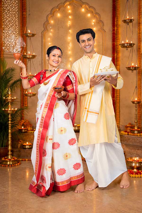 Indian couple celebrating Durga Puja with incense and sweets at home