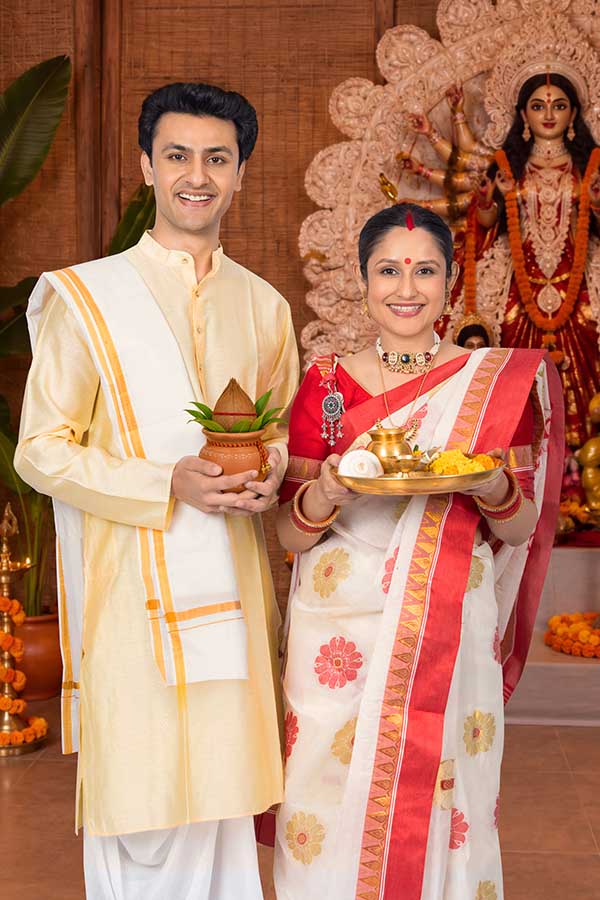 Indian couple performing Durga Puja rituals with kalash and worship thali