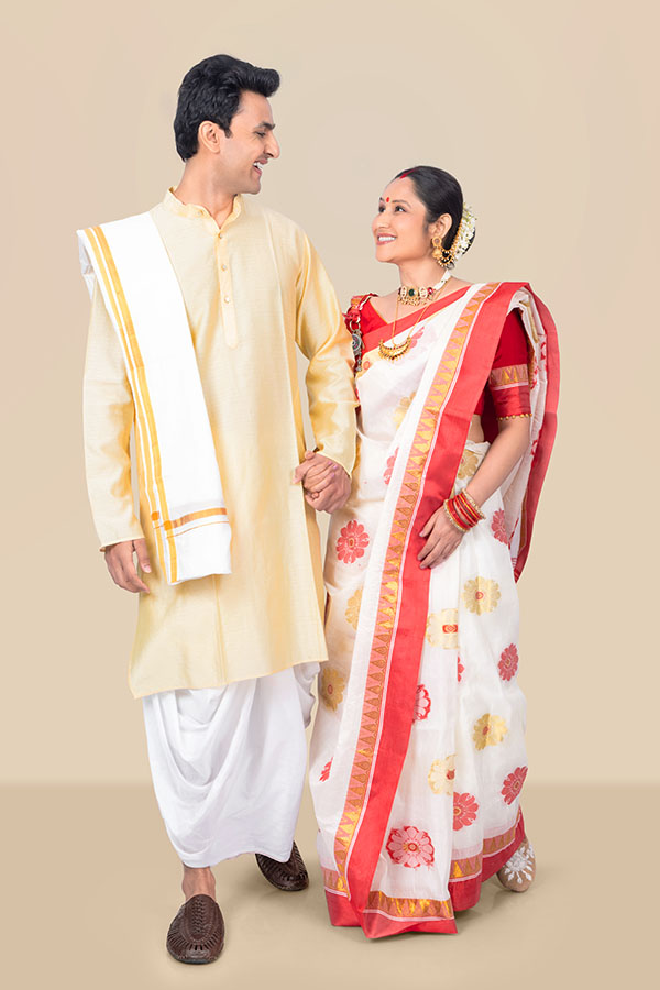 Indian couple holding hands and celebrating Durga Puja in traditional attire