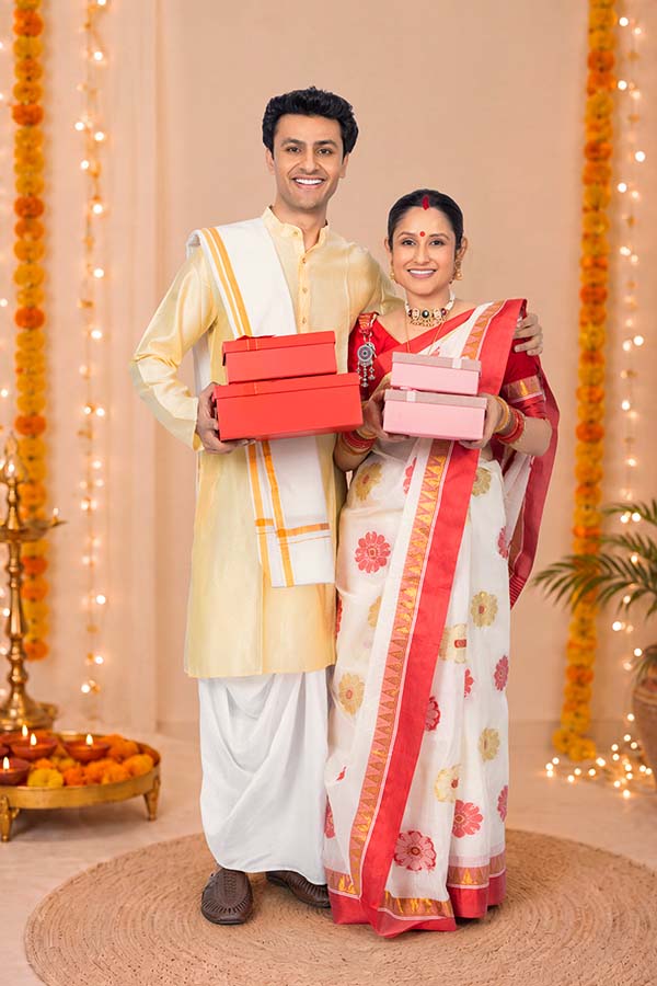 Indian couple exchanging festive gift boxes during Durga Puja
