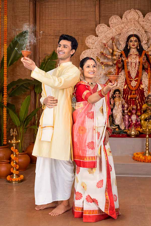 Indian couple performing Dhunuchi ritual before Goddess Durga