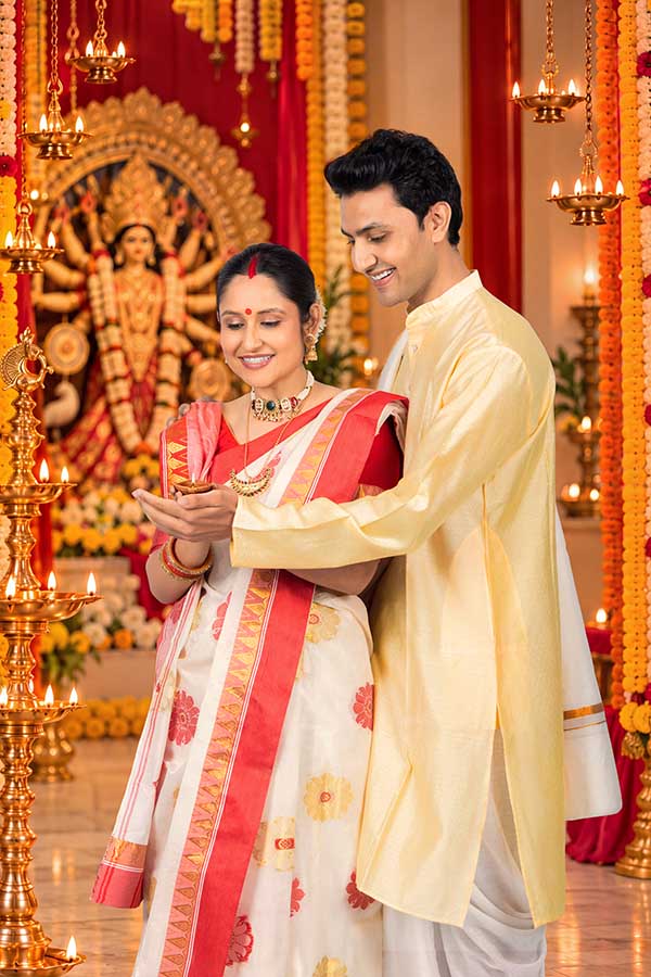 Indian couple performing devotional lamp ritual during Durga Puja celebration