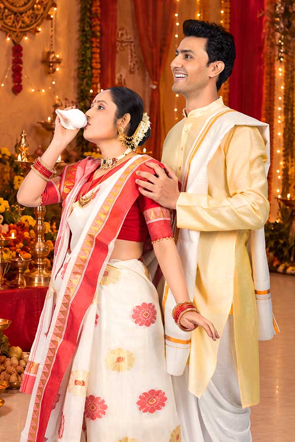 Indian couple performing conch shell ritual during Durga Puja celebration