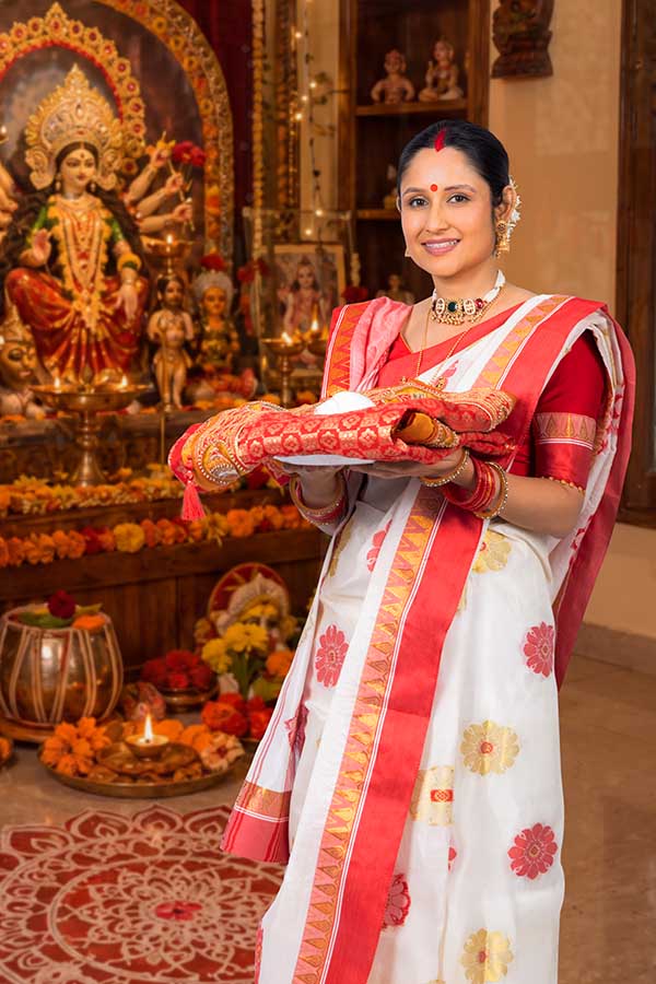 Indian woman holding traditional textile offering during Durga Puja