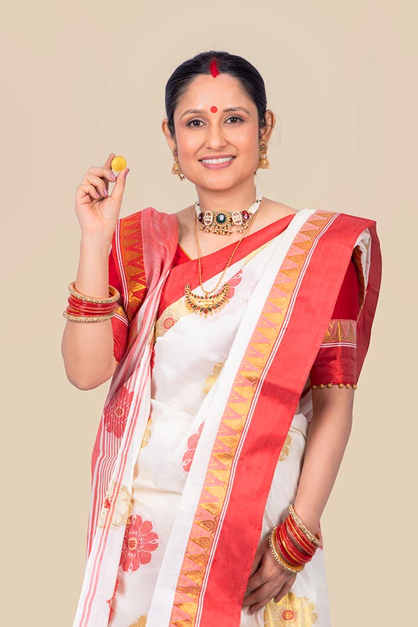 Indian woman holding gold coin in traditional Durga Puja attire