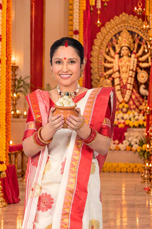 Bengali woman offering traditional sweets during Durga Puja celebration