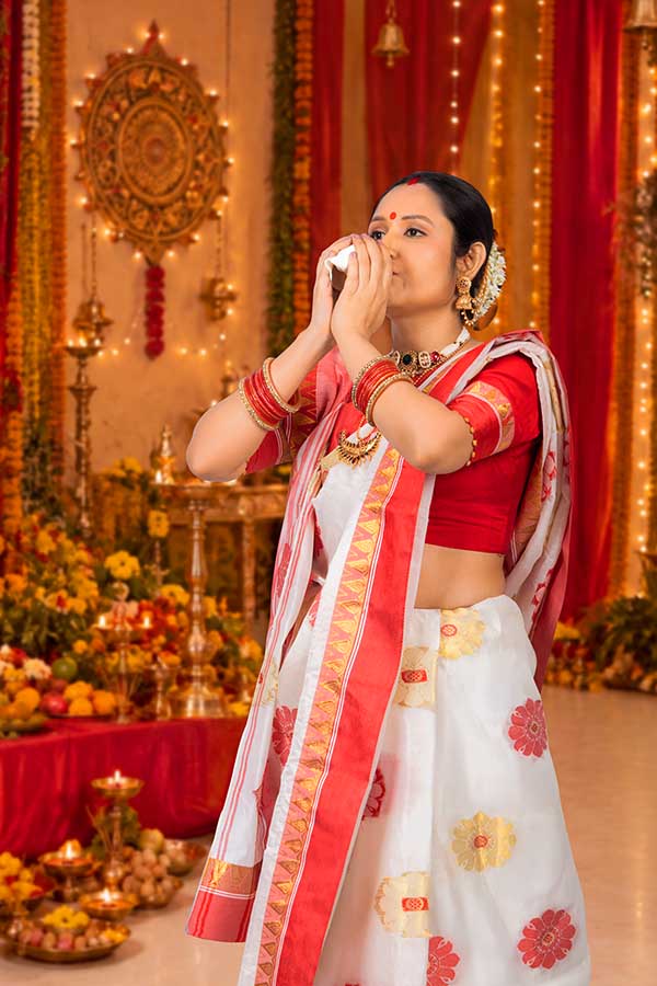 Indian woman blowing conch shell during Durga Puja celebration