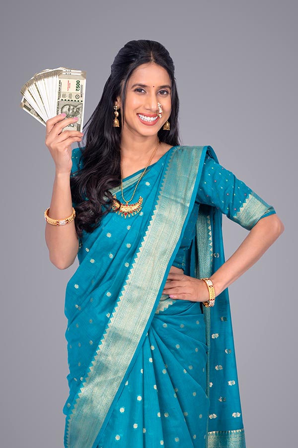 Indian woman holding currency notes and smiling confidently