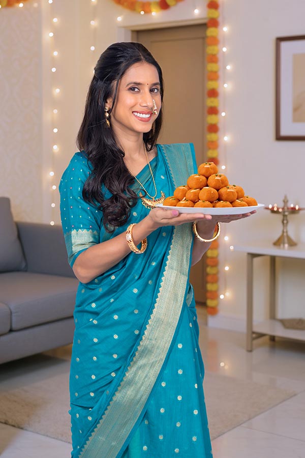 Indian woman serving festive laddus during traditional celebration