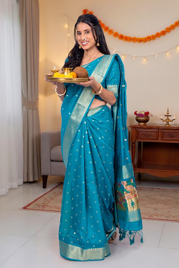 Indian woman in traditional saree holding festive puja thali at home