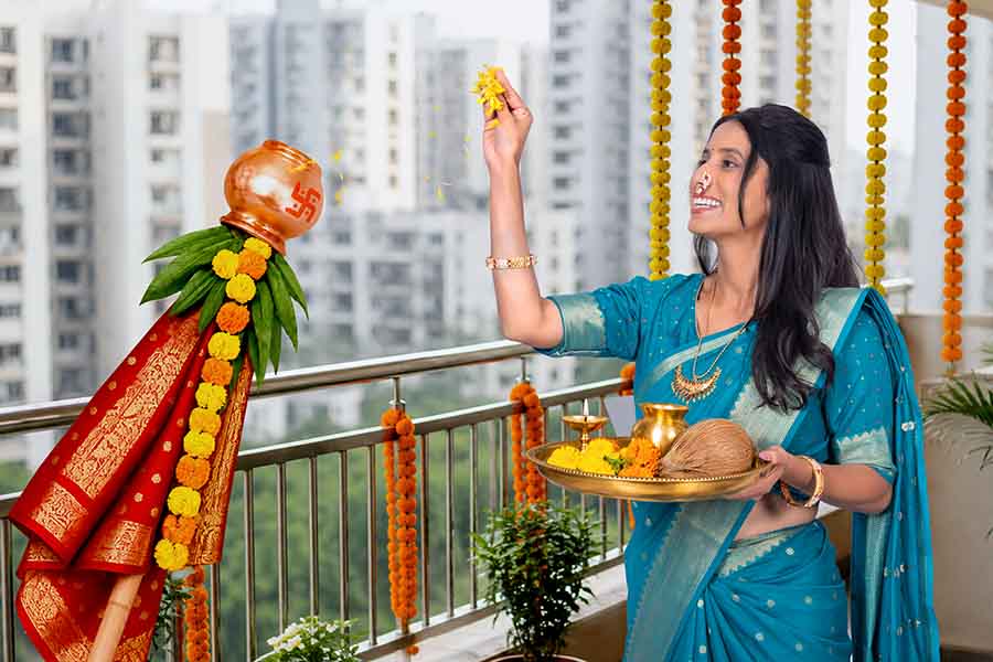 Indian woman performing Gudi Padwa ritual with puja thali on home balcony
