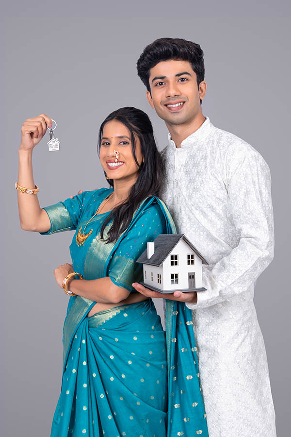 Indian couple holding house model and keys for new home ownership