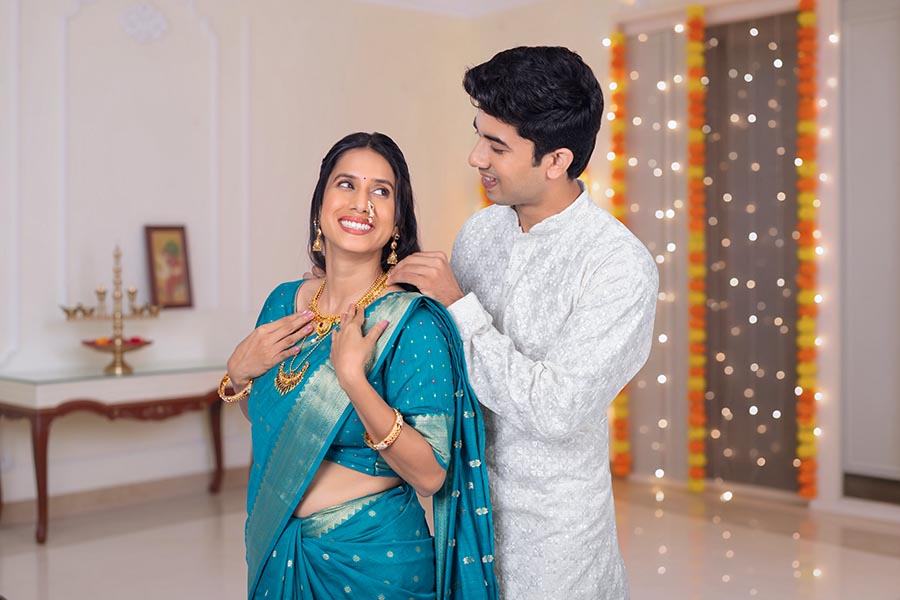 Indian husband gifting jewellery to wife during festive celebration at home