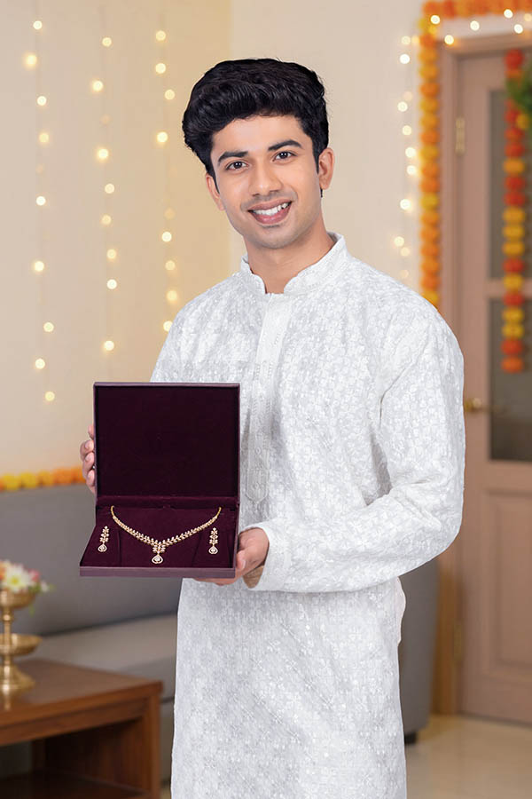Indian man displaying jewelry gift box during festive celebration
