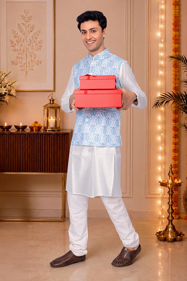 Young Indian man carrying festive gift boxes at decorated home