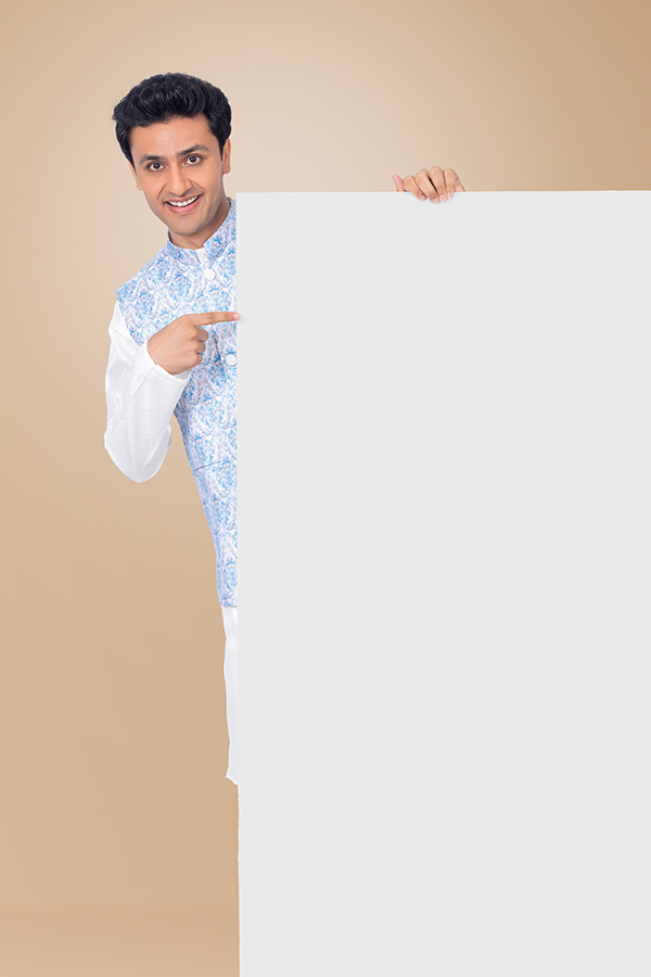 Indian man pointing towards blank promotional board in festive attire