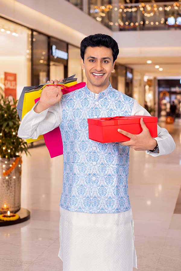 Indian man carrying shopping bags and festive gift box at mall