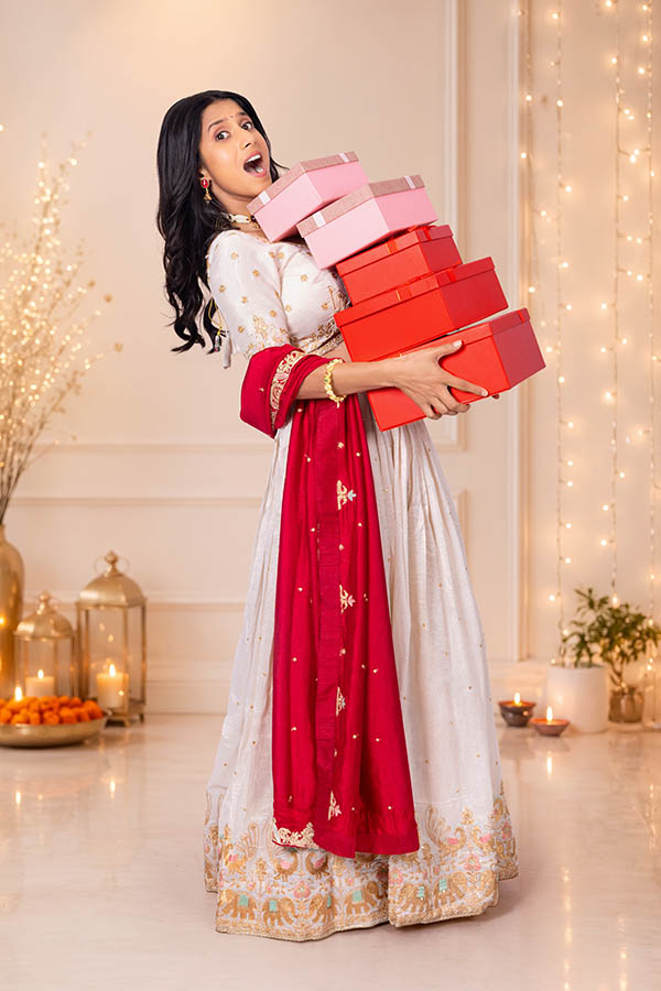 Surprised Indian woman carrying festive gift boxes during celebration