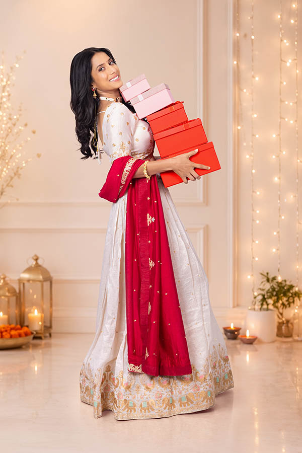 Happy Indian woman carrying festive gift boxes with elegant smile