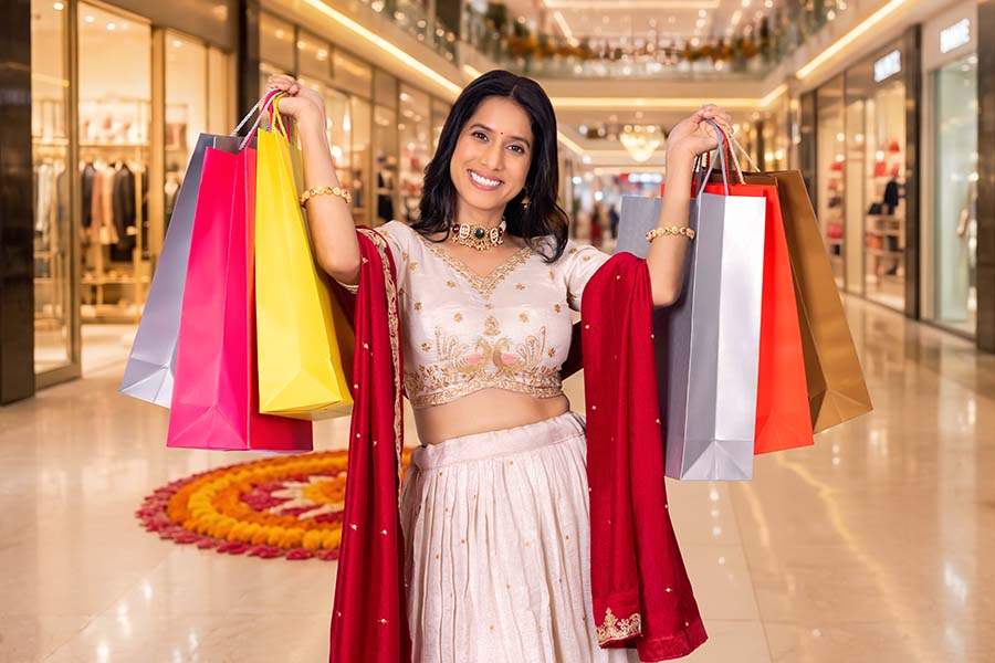 Smiling Indian woman holding festive shopping bags at mall