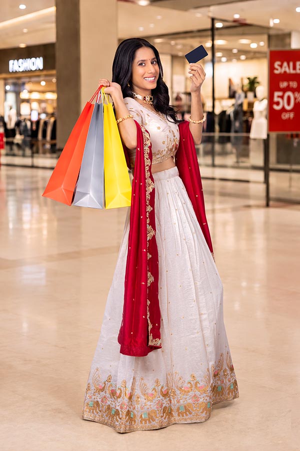 Indian woman holding shopping bags and credit card after festive purchase