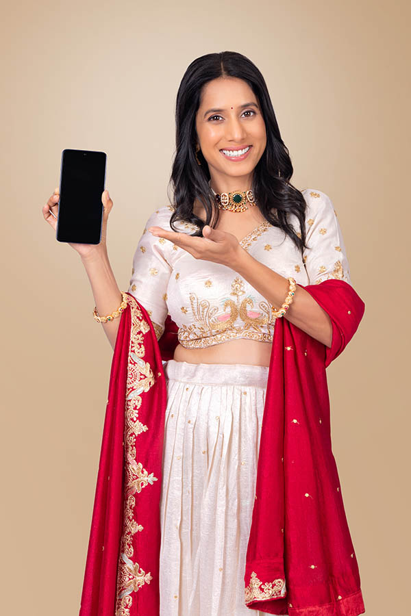 Indian woman presenting smartphone with blank screen for festive promotion