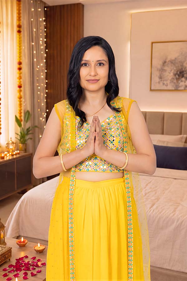 Indian woman in traditional attire offering festive Namaste greeting at home