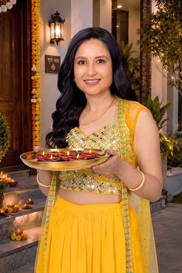 Indian woman holding decorated diya platter for Diwali welcome ritual