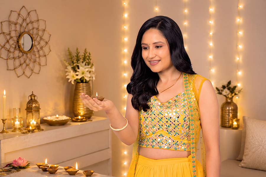 Indian woman admiring glowing diya during peaceful Diwali celebration indoors
