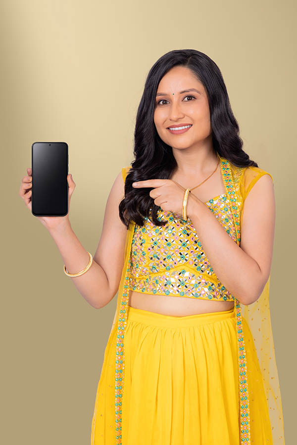 Indian woman pointing at blank smartphone screen in traditional festive outfit