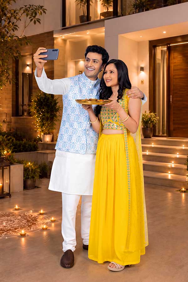 Indian couple taking festive selfie with puja thali during Diwali